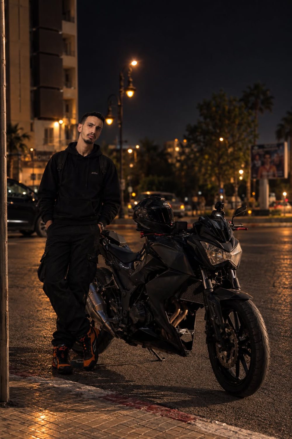 Yasser Ajana standing beside his motorcycle at night in Tangier